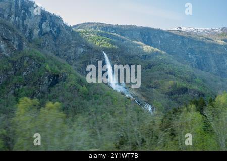 Der Wasserfall Rjoandefossen stürzt einen steilen Berghang hinunter und bietet den Passagieren an Bord der Flåm-Bahn einen atemberaubenden Anblick. Diese kraftvolle Wa Stockfoto