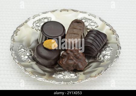 Verschiedene Arten von Schokoladenpralinen auf einer Silberplatte, Nahaufnahme, isoliert auf weißem Hintergrund Stockfoto