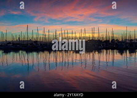 Segelboote, die in der Bucht von San Francisco mit lebendigem Dämmerungshimmel und Wasserreflexionen vor Anker gehen. Emeryville, Alameda County, Kalifornien, USA. Stockfoto