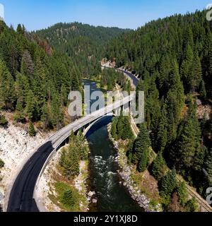 Die gewundene Straße führt durch einen Wald von Idaho mit Rainbow Bridge Stockfoto