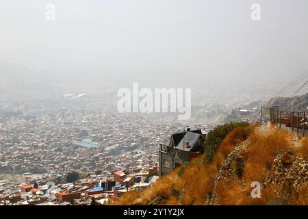 La Paz, BOLIVIEN; 8. September 2024: Rauch durch Waldbrände im bolivianischen Tiefland Amazonas und Yungas bedeckt die Stadt in einem dichten Dunst, der die nahe gelegenen Hügel und Berge verdeckt. Mehrere hundert Waldbrände brennen derzeit in der Tiefebene; Global Forest Watch hat im Jahr 2024 in Bolivien bisher 29.011 VIIRS-Brandalarme registriert (ein Rekord). Dieser Blick blickt nach Südosten über die Vororte der Stadt in Richtung des unteren Teils der Stadt Zona Sur. Normalerweise wäre der Illimani, Boliviens zweithöchster Gipfel, in dieser Ansicht deutlich zu sehen. Stockfoto