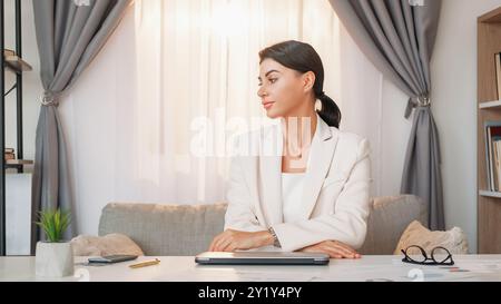 Beenden Sie die Arbeit. Entlastete Frau. Deadline-Projekt. Eleganter, abgenutzter Frauensessel mit geschlossenem Laptop in hellem Bürozimmer. Stockfoto