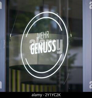 Aufkleber am Schaufenster eines Ladens mit der deutschen Inschrift mehr Genuss. Übersetzung: Mehr Vergnügen Stockfoto