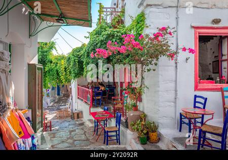 Chora von Amorgos, Griechenland - 27. Juli 2024: Enge Kopfsteinpflasterallee mit weiß getünchten Häusern und Cafés im Freien in der Hauptstadt der Ägäis. Stockfoto