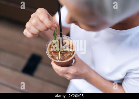 Nahaufnahme von oben auf eine nicht erkennbare Frau, die am Sommertag eine Tasse Eiskaffee mit Strohhalm in der Stadt hält. Tasse kalten Bubble Tee mit Strohhalm Stockfoto