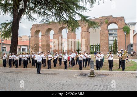 Rom, Italien. September 2024. Die Band der Stadtpolizei von Roma Capitale konzertiert vor den Überresten des Aquädukts auf der Piazza Pepe anlässlich der Feierlichkeiten zum 150-jährigen Bestehen des Stadtteils Esquilino in Rom. Das Viertel Esquilino feiert 150 Jahre seit seiner Umwandlung in ein modernes Viertel. Als multiethnisches Viertel und Symbol der kulturellen Integration verdankt es seinen Namen der antiken römischen Kaserne der kaiserlichen Pferdewache, die auf seinem Territorium präsent ist: castra priora equitum singularium. Viele der wichtigen antiken Überreste wurden von der Residenzstadt erstickt Stockfoto