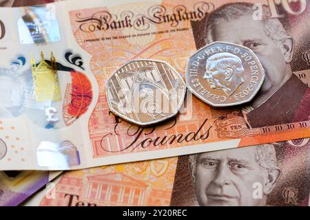 Nahaufnahme britischer 10-Pfund-Banknoten und 50-Pence-Münzen mit dem Porträt von König Karl III., Teil der Aktualisierung der britischen Währung von 2024. Stafford, Vereinigte Staaten Stockfoto