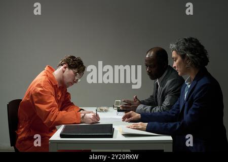 Multirassisches Team von Fachleuten, die Dokumente überprüfen und Strategien in modernen Büroumgebungen unter künstlicher Beleuchtung diskutieren Stockfoto