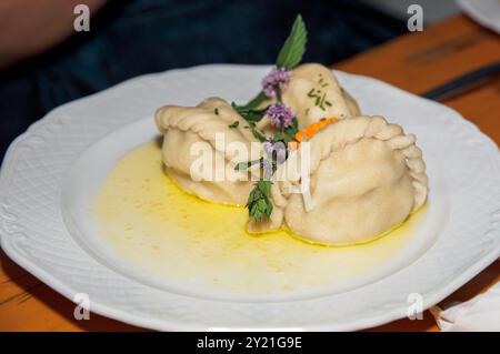 Nahaufnahme traditioneller Klöße mit Kräutern, serviert auf weißem Teller, mit köstlichem Essen, kulinarischem Kunstkonzept Stockfoto