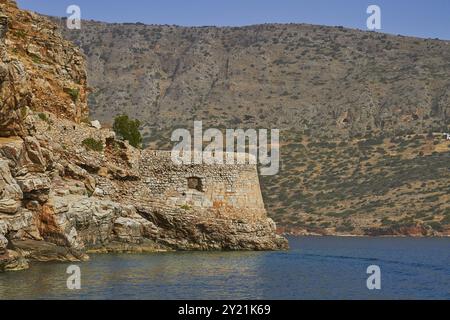 Alte Festung in felsiger Küstenlandschaft umgeben von hügeligem Gelände und ruhigem blauem Wasser, venezianische Meeresfestung, Leper Island, Spinalonga, Elounda Stockfoto