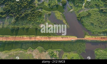 Aus der Vogelperspektive auf Transpantaneira unbefestigte Straße, die einen Fluss durch eine hölzerne Brücke überquert, üppige Vegetation rund um die North Pantanal Feuchtgebiete, Mato Grosso, Brasilien, Also Stockfoto