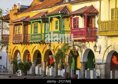 Aus nächster Nähe sehen Sie farbenfrohe historische Gebäude mit Balkonen und Bögen im warmen Sonnenlicht, Plaza de los Coches (Kutschenplatz), Cartagena, UNESCO wo Stockfoto