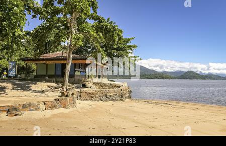 Idyllischer Blick auf eine Strandhütte mit grünen Bäumen, Meer und Bergen im Hintergrund, Jabaquara, Brasilien, Südamerika Stockfoto