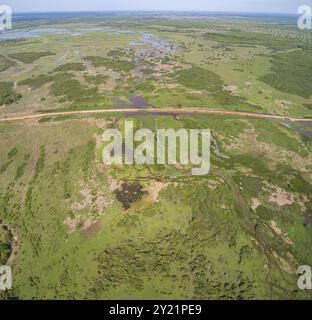 Luftaufnahme der Transpantaneira-Feldstraße, die eine Lagune über eine kleine Brücke in der typischen Landschaft der North Pantanal Feuchtgebiete, Mato Grosso, Brazi, überquert Stockfoto