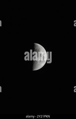 Wachsender Mond, Hochformat-orientiertes Bild mit Mond isoliert auf schwarzem Hintergrund mit Text oder Kopierraum Stockfoto