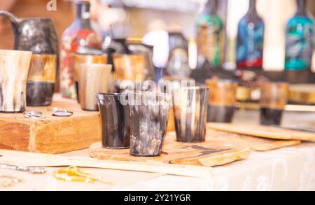 Handgefertigte Hornbecher, hölzerne Servierbretter, handwerkliche Marktpräsentation, bunte Flaschen, traditionelle Handwerkskunst, handgefertigtes Konzept Stockfoto