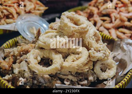 Ein Korb mit gebratenem Calamari-Snack, der auf einem traditionellen Markt verkauft wird. Stockfoto