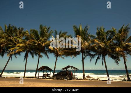 Erholsame Holzhütten unter Kokospalmen an einem Strand mit Blick auf den Indischen Ozean in Kotakarang, Pesisir Barat, Lampung, Indonesien. Stockfoto