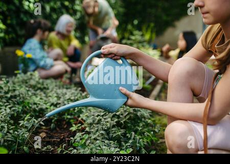 Schulmädchen bewässern Pflanzen im Schulgarten während einer nachhaltigen Freiluft-Bildungsveranstaltung. Das Konzept des Erfahrungslernens und der Ekliteration. Stockfoto