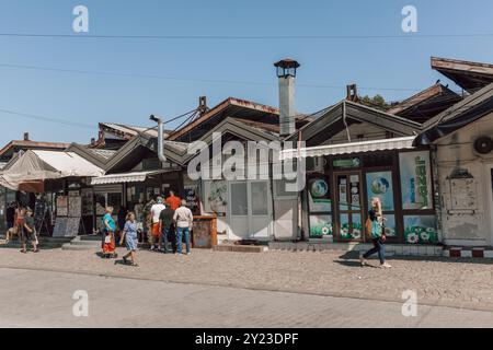 Eine Straßenszene in der Nähe des Marktes in der serbischen Stadt NIS an einem sonnigen Tag mit blauem Himmel und Menschen, die vor den Geschäften und kleinen Restaurants spazieren gehen. Stockfoto