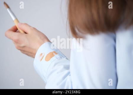 Frau, die tagsüber ein hellblaues Hemd in einem gut beleuchteten Raum mit einem Pinsel aufträgt. Alltagsbeizkonzept. Hohe Qualität p Stockfoto