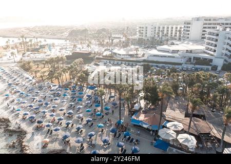 Touristen, die sich am Strand von Nissi entspannen, mit Hotels und Resorts im Hintergrund. Ayia Napa, Zypern Stockfoto