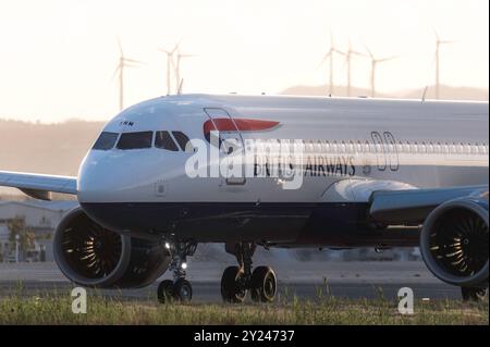 Larnaca, Zypern - 24. Mai 2024: British Airways Airbus bei Sonnenuntergang in der Nähe von Windturbinen Stockfoto