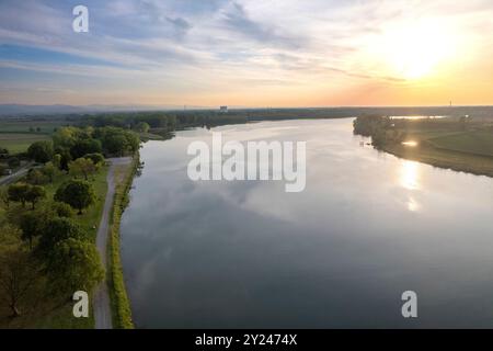 Aus der Vogelperspektive auf einen Fluss, der sich bei Sonnenuntergang durch die üppige Natur schlängelt und die Farben des Abendhimmels reflektiert Stockfoto