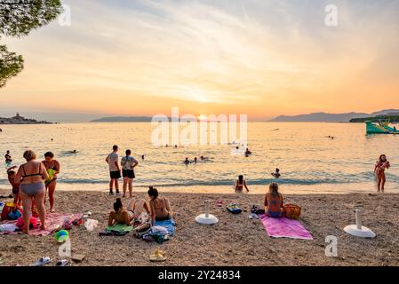 Menschen beobachten den Sonnenuntergang am Strand von Makarska riviera an der Adria, Dalmatien Region in Kroatien, am 24. August 2024 Stockfoto