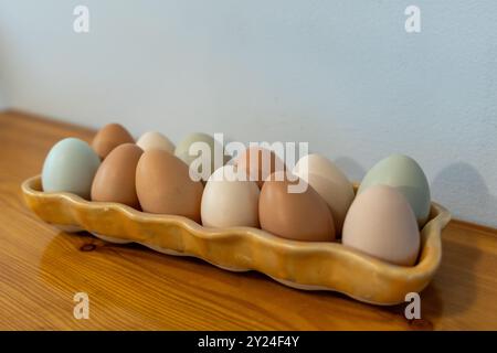 Mehrfarbige Eier in einem Keramiktablett auf Holzoberfläche Stockfoto