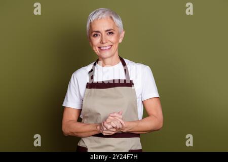 Foto von guter Stimmung attraktive Dame gekleidete Schürze, die Getränke vorbereitet lächelnder leerer Raum isolierter grüner Farbhintergrund Stockfoto