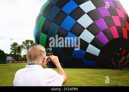 Ein Mann, der ein Foto von einem Heißluftballon macht, der sich aufbläst. Stockfoto