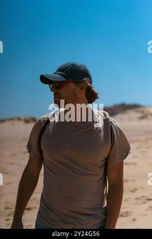 Ein Mann mit Baseballmütze geht am Strand spazieren, Cascais. Stockfoto