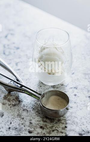 Vanilleeis im Glas mit einer Schaufel auf einer Marmorplatte Stockfoto