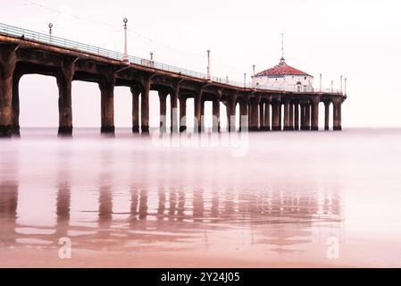 Ruhiger Pier über stillen Meeresgewässern mit sanften Reflexen bei Sonnenuntergang. Stockfoto