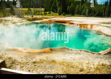 Lebendige heiße Quelle mit türkisfarbenem Wasser und orangen Mineralablagerungen. Stockfoto