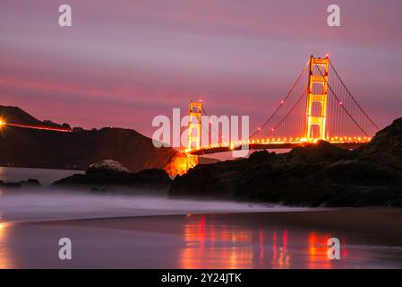 Golden Gate Bridge beleuchtet bei Sonnenuntergang mit Reflexion im Wasser. Stockfoto