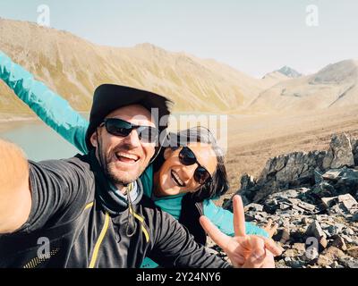 Close Up junge glückliche kaukasische aktive Millennial Paare Influencer machen Smartphone-Selfie, während sie Spaß auf einer Wanderung in die Natur haben und Berge erreichen Stockfoto