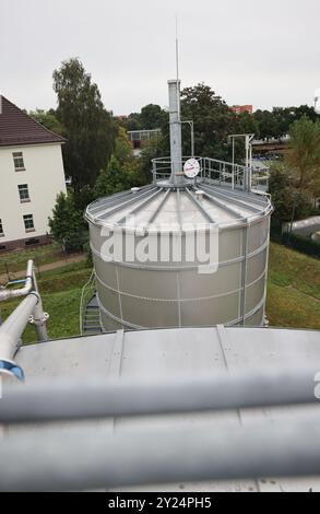 Hamburg, Deutschland. September 2024. Blick über das Schwarzwasserreservoir zu einem Biogasspeicher (Jenfelder Energiespeicher JENS) in einem Wohn- und Gewerbegebiet im Stadtteil Jenfeld. Die erste Abwasseraufbereitungsanlage von Hamburg Wasser wurde am Montag symbolisch in Betrieb genommen. Die Recyclinganlage „GRE-Y“ wandelt gebrauchtes Dusch- und Spülwasser aus dem Wohngebiet Jenfelder Au in Prozesswasser um, das zur Spülung von Toiletten und zur Bewässerung von Grünflächen genutzt wird. Quelle: Christian Charisius/dpa/Alamy Live News Stockfoto