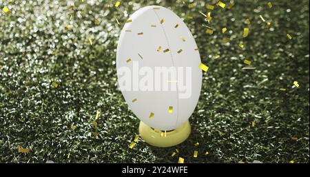 Bild von Konfetti über weißem Rugbyball auf Gras Stockfoto