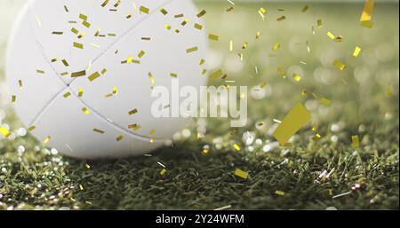 Bild von Konfetti über weißem Rugbyball auf Gras Stockfoto