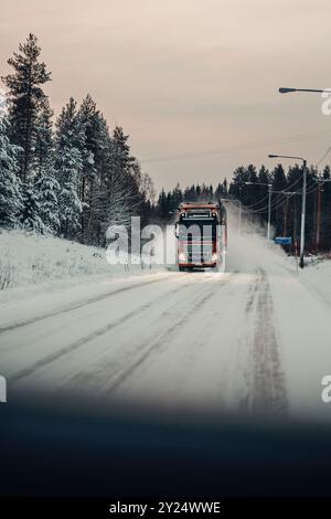 Roter Lastwagen auf vereister Straße durch die arktische Tundra in Rovaniemi, Lappland Stockfoto