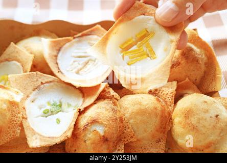 Handpflückende Kürbis-Topping Kanom Krok, thailändischer Kokosnussmilchpfannkuchen, eines der beliebtesten Straßenessen in Thailand Stockfoto