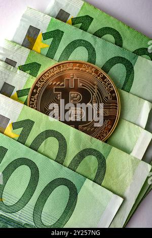 Bitcoin-Goldmünzen mit Euro-Banknoten auf weißem Hintergrund, Nahaufnahme. Stockfoto