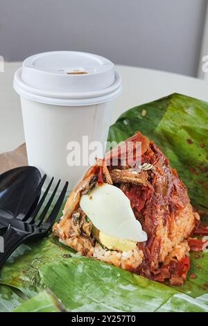 Einfache, authentische Portion von Nasi Lemak Bungkus, populärem Reis mit Kokosmilch und Sambal Chili, Sardellen und Eiern in Bananenblatt gewickelt Stockfoto