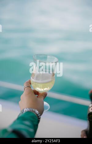 Hand einer Dame mit einem Glas Champagner auf einer Bootsparty in Jomtien, Chonburi, Thailand Stockfoto