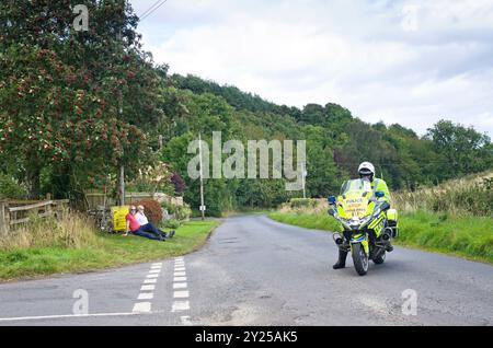 Zwei Zuschauer warten geduldig am Straßenrand auf die Ankunft der Fahrer in der 1. Etappe des Men's Tour of Britain Cycle Race 2024. Stockfoto