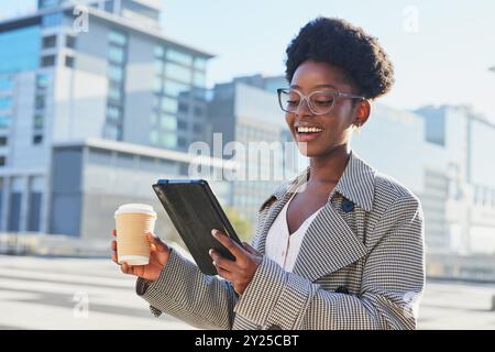 Glückliche Geschäftsfrau, die Kaffee und Tablet in urbaner Umgebung genießt Stockfoto
