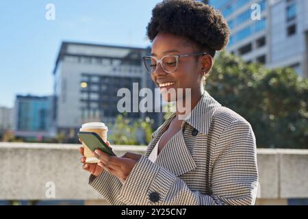 Selbstbewusste Frau, die Kaffee und Smartphone im Freien genießt Stockfoto
