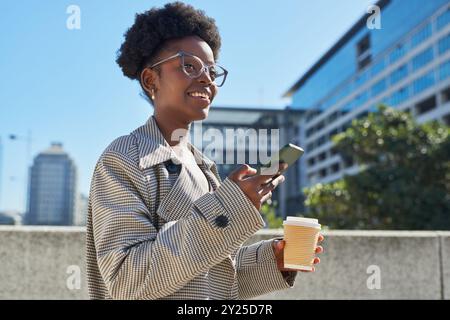 Junge Frau genießt Kaffee und Smartphone in der modernen Stadt Stockfoto